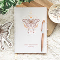 Daily reflection journal with luna moth design and rose gold pen on textured surface
