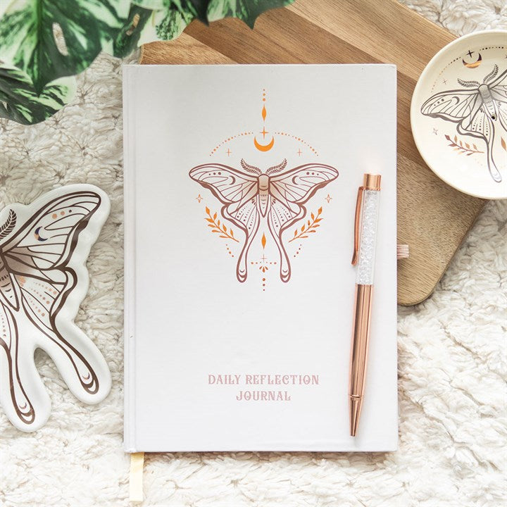 Daily reflection journal with luna moth design and rose gold pen on textured surface