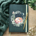 Notebook with fox illustration on a wooden surface with a pen and green fabric.