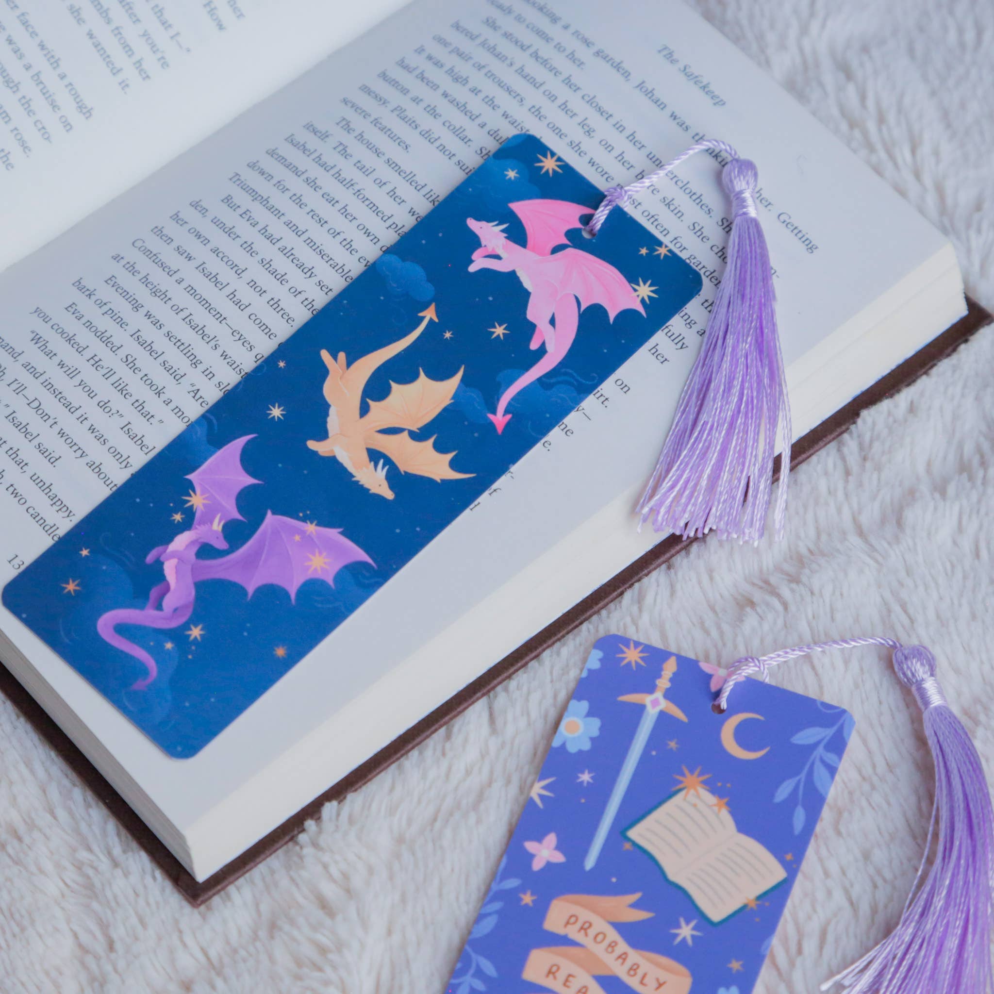Two dragon-themed bookmarks with tassels on an open book.
